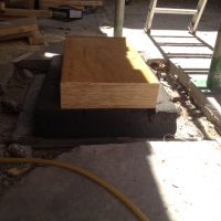 pied d'un poteau avec ses 10cm d'isolant rigide de fibre de verre (en noir, genre de mousse rigide, très résitante à la compression mais très friable) et le plot en bois.