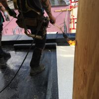 couvreur en train d'installer une bande de membrane du toit